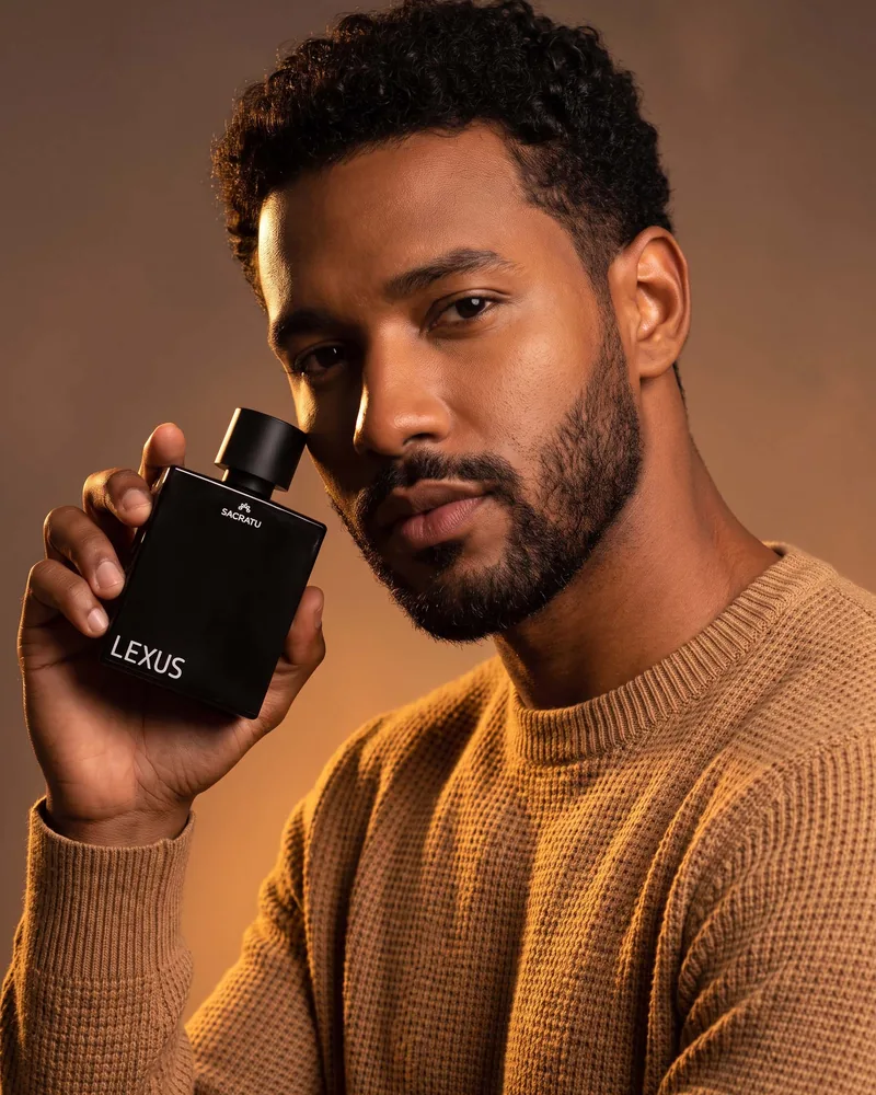 Homem segurando o perfume Lexus, da Sacratu, junto ao rosto